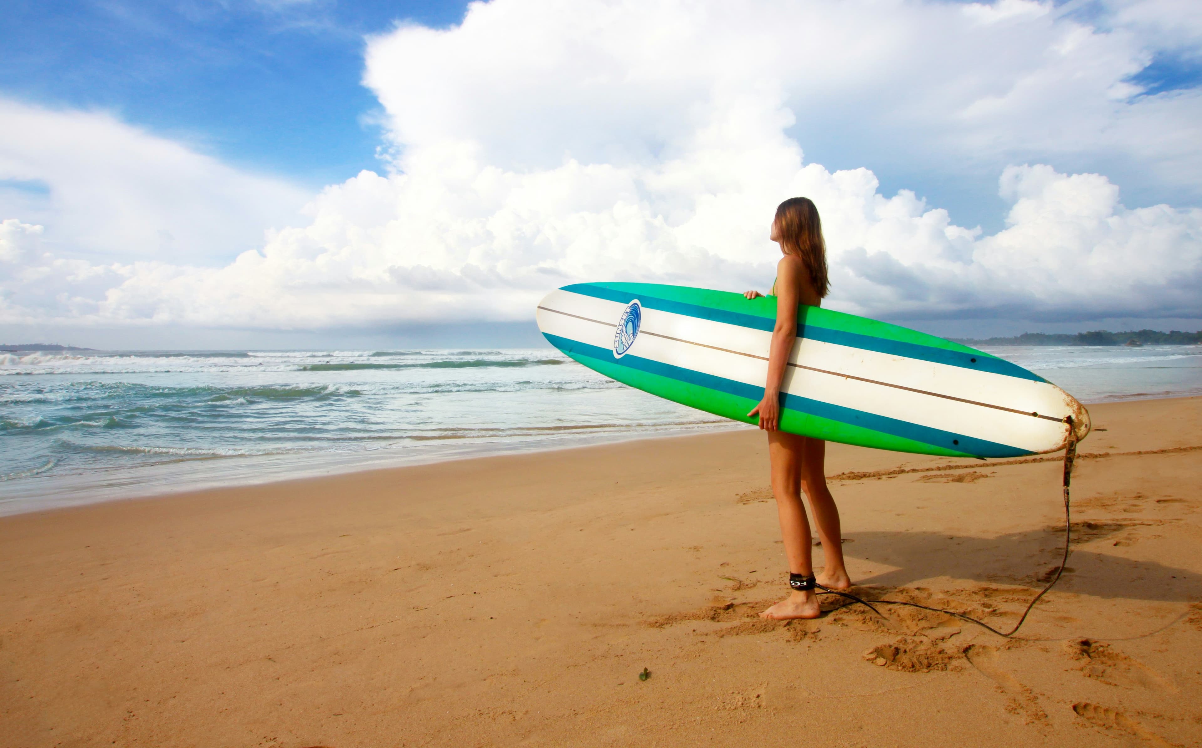 A surfer carrying a board along the sea