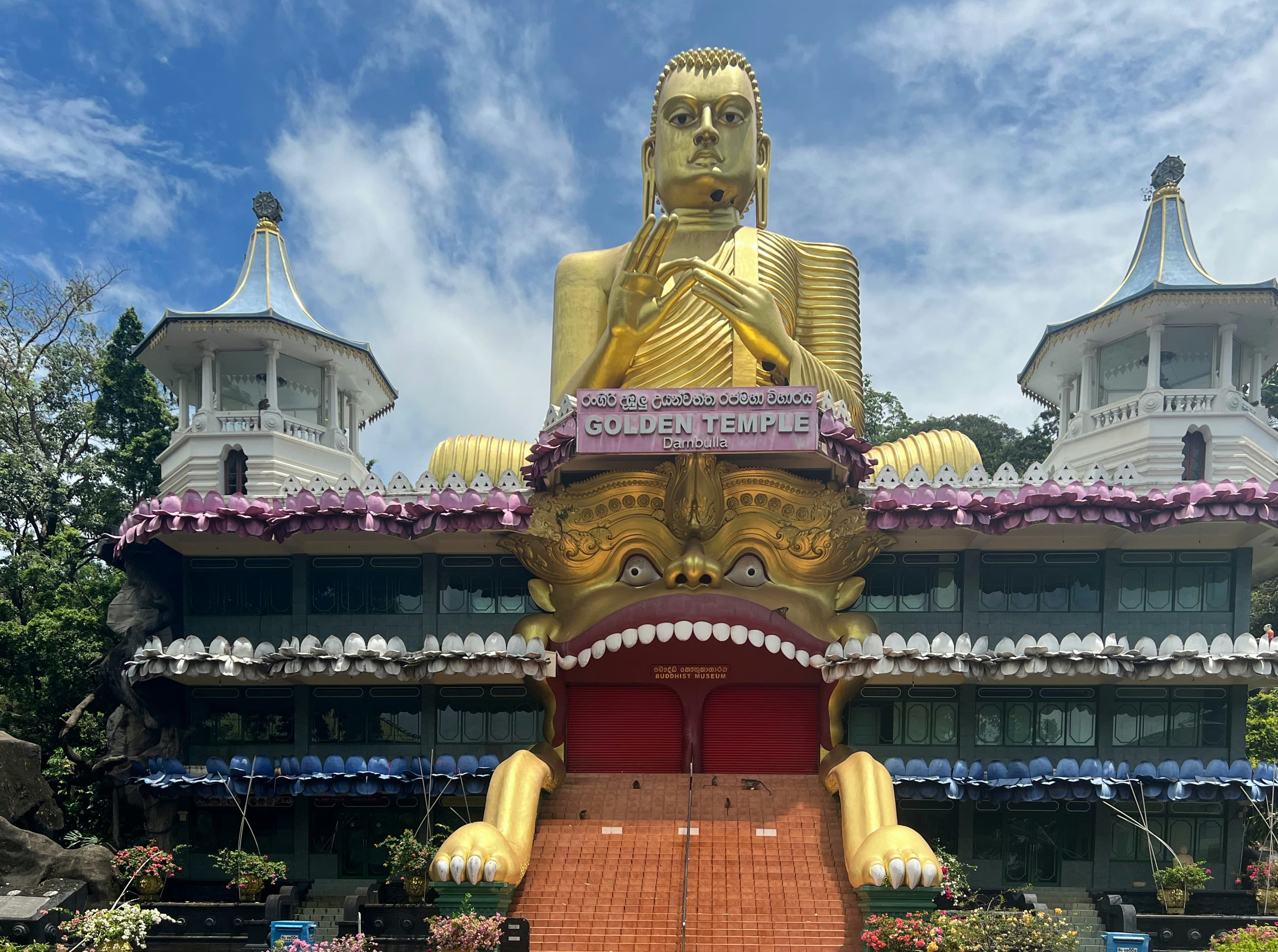 A large statue in front of the temple building at Dambulla