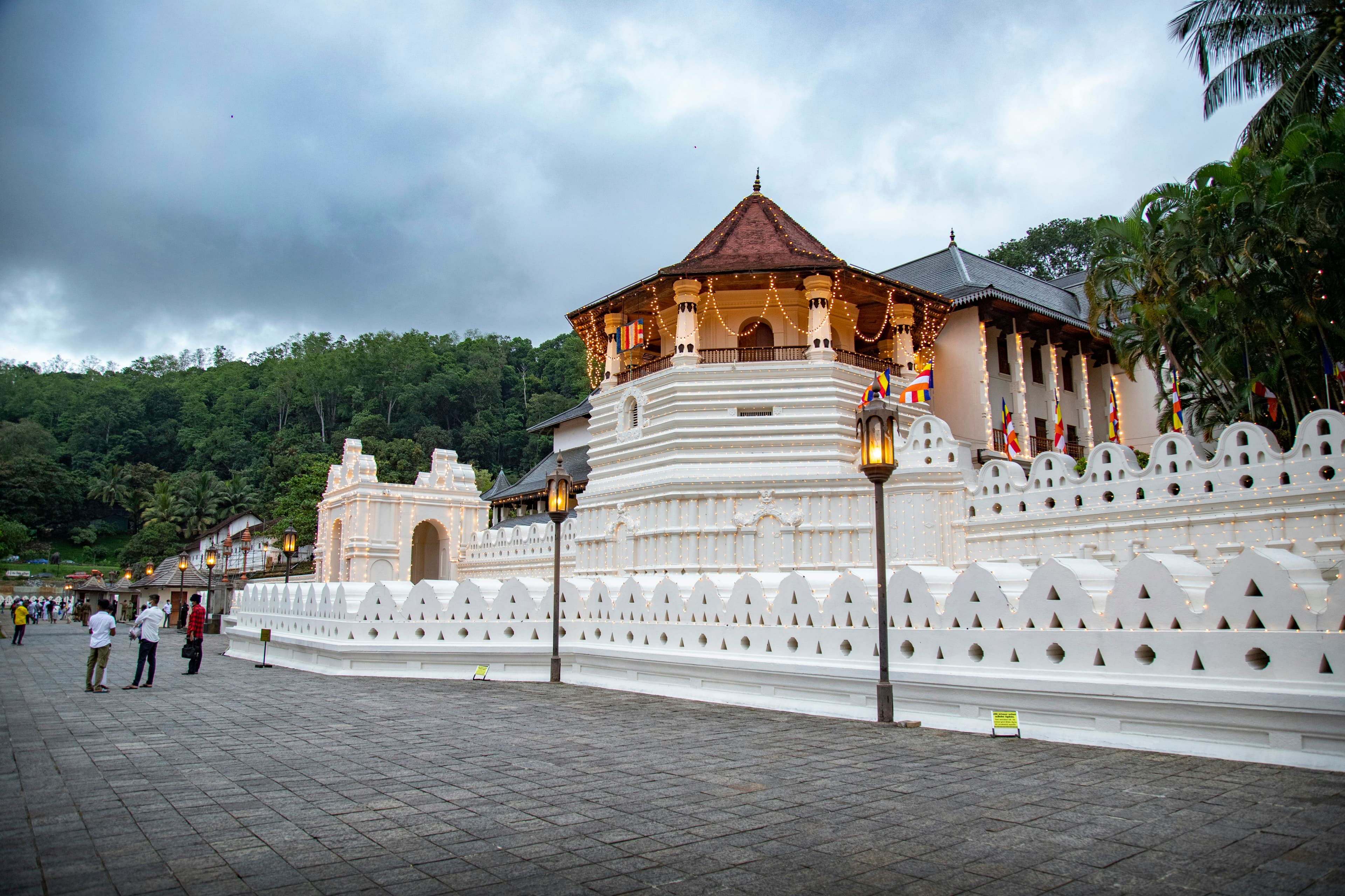 A white building with a gold roof beside the Temple of the Tooth in Kandy